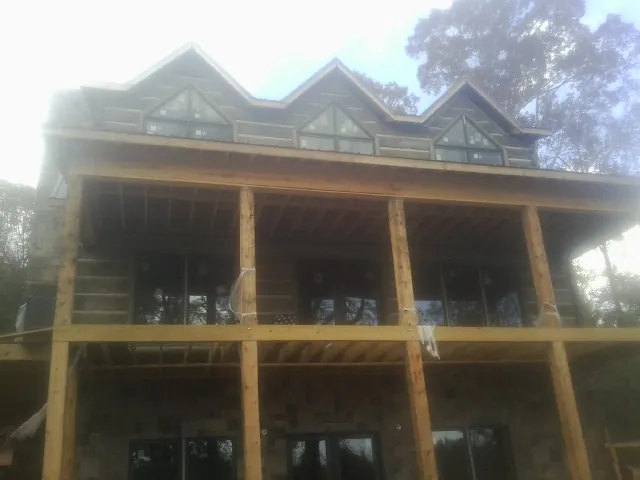 Dormers and porch framing on a large log home under construction — Roof Coating work by our crew in Elizabeth City