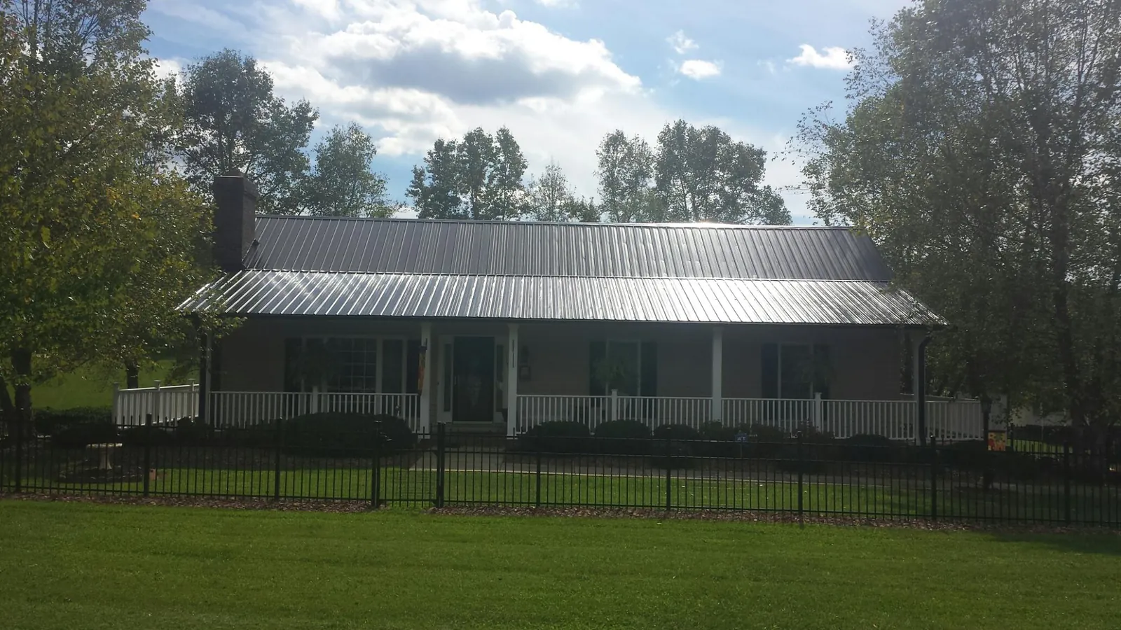 Gray metal roof on a brick ranch with a full width front porch — Gutter Guard Installation work by our crew in Elizabeth City