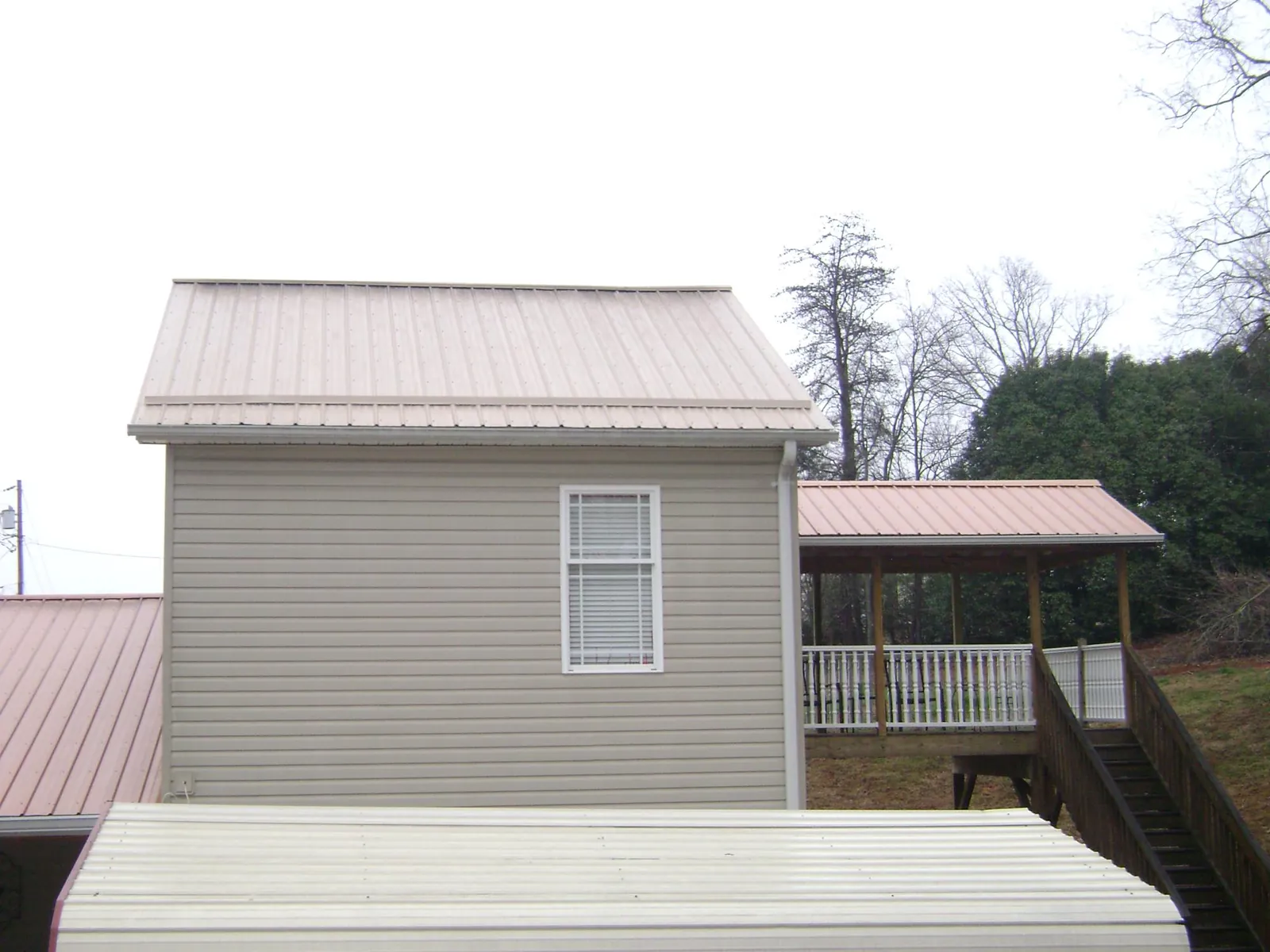 Tan metal roofs on a two story addition and attached porch, from a Roof Replacement job in Elizabeth City