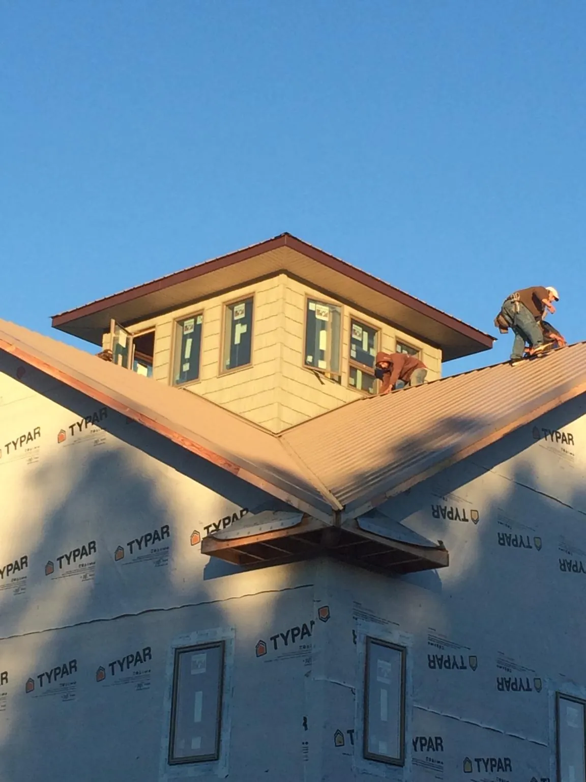 Roofers working around a rooftop cupola on a new metal roof at sunset — Roof Waterproofing in Elizabeth City by Roofing Brothers